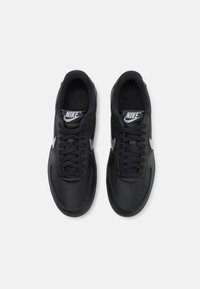 Sapatos atléticos pretos com um cabedal sintético suave, língua almofadada e fecho de atacadores. Apresenta um swoosh branco da Nike e uma sola texturizada.
