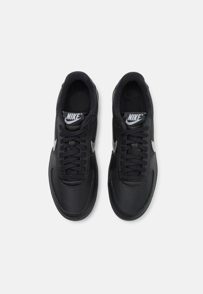 Scarpe sportive nere con tomaia in sintetico liscio, linguetta imbottita e chiusura con lacci. Presentano un logo Nike bianco e una suola testurizzata.