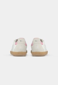 Λευκά δερμάτινα παπούτσια με σόλες από καουτσούκ γκρίζα, που διαθέτουν ροζ λεπτομέρειες στην φτέρνα και υφή. Απλός, χαμηλού προφίλ σχεδιασμός.