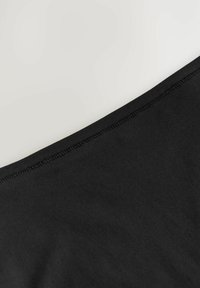 Zwarte stof met een gladde textuur en een strak afgewerkte, ronde halslijn. Gestikte randen zijn zichtbaar en tonen een minimalistisch ontwerp.