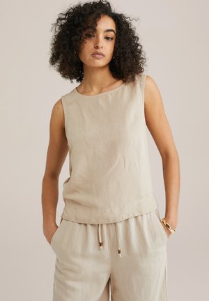 Beige mouwloze top gemaakt van lichtgewicht stof, met een gladde textuur, ronde halslijn en een ontspannen pasvorm. Gecombineerd met bijpassende broek.