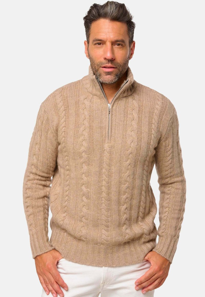 Pull en tricot beige avec un col zippé à quart, présentant des motifs texturés et des poignets et un ourlet côtelés. Tissu en fil doux.