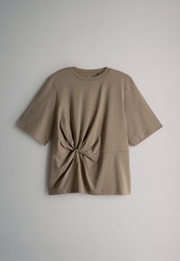 Khaki T-shirt with short sleeves, featuring a knotted twist detail at the waist, made of soft fabric with a smooth texture.