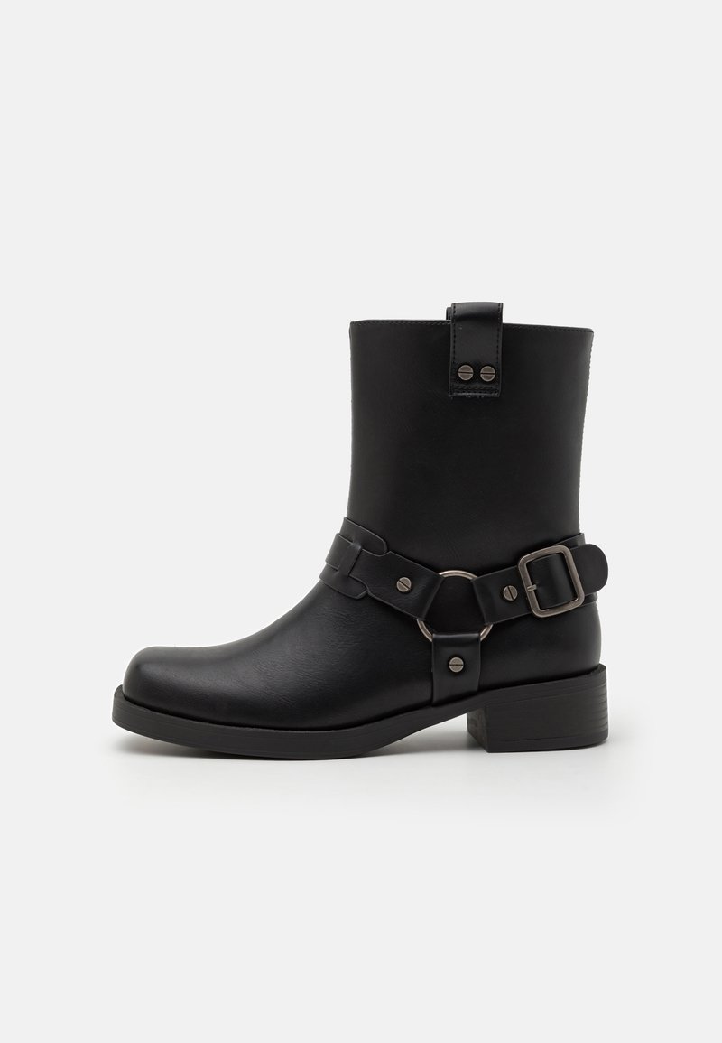 Black leather ankle boot with a square toe, rounded heel, decorative strap and buckle detail, and metal accents. Smooth texture.