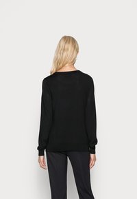 Schwarzer Strickpullover mit langen Ärmeln und rundem Halsausschnitt, mit lockerer Passform und geripptem Saum, von hinten gezeigt.
