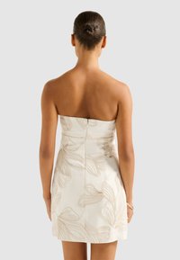 Weißes trägerloses Kleid mit beiger floraler Stickerei, tailliertem Oberteil und ausgestelltem Rock. Zeigt die Rückansicht, glattes Material und subtilen Glanz.