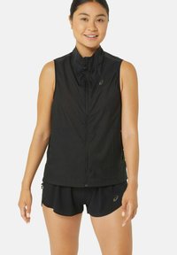 Gilet da corsa senza maniche nero, in tessuto leggero, con zip frontale a tutta lunghezza, colletto alto, dettaglio logo discreto sul petto, abbinato a pantaloni corti neri.
