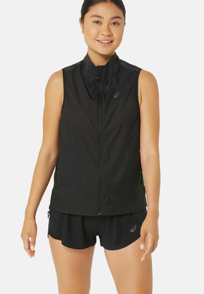 Gilet da corsa senza maniche nero, in tessuto leggero, con zip frontale a tutta lunghezza, colletto alto, dettaglio logo discreto sul petto, abbinato a pantaloni corti neri.
