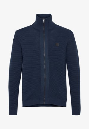 Marineblaue Zip-up-Jacke aus strukturiertem Strickmaterial, mit hohem Kragen, gerippten Bündchen und kleinem Logo auf der Vorderseite.