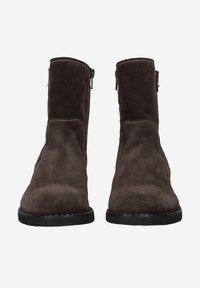 Bottes cheville en daim marron avec fermeture éclair latérale et semelle en caoutchouc noire texturée, dotées d'une tige lisse et de coutures contrastées.
