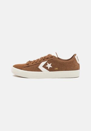 Niski brązowy zamszowy sneaker z białym logo gwiazdy po boku i białą gumową podeszwą, widziany od strony zewnętrznej.