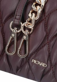 Burgunderfarbene Lederhandtasche mit gestepptem Design, ausgestattet mit einer Kette in Goldoptik, Metallschnallen und einem markierten Schild mit "PICARD."