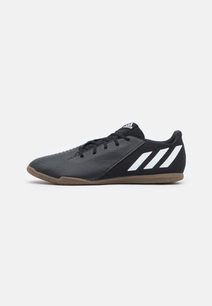 Scarpa da calcio indoor Adidas nera e marrone con il logo a tre strisce bianco e lacci neri, mostrata di profilo su sfondo bianco.