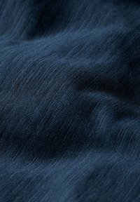 Tejido de un azul marino profundo con una superficie texturada, que muestra finas y sutiles estrías y una apariencia suave y tejida. Sin patrones ni acentos visibles.