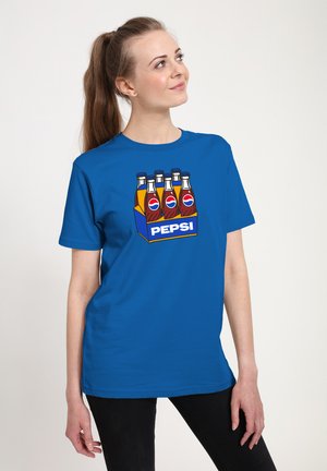 Young woman with long ponytail wearing a blue t-shirt featuring a cartoon six-pack of Pepsi bottles.