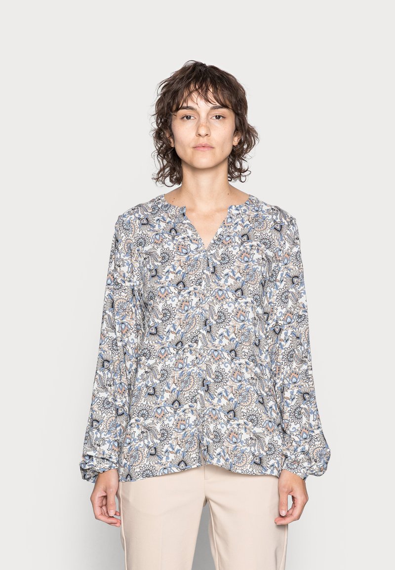 Blusa com padrão floral, com decote em V, mangas longas e um tecido suave e leve em tons de azul, bege e branco.