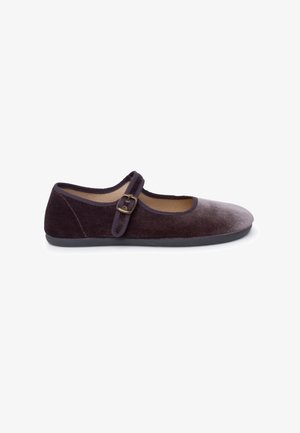 Zapato Mary Jane en terciopelo morado oscuro con punta redondeada, correa ajustable con hebilla y un interior suave de color beige, descansando sobre una suela de goma oscura.