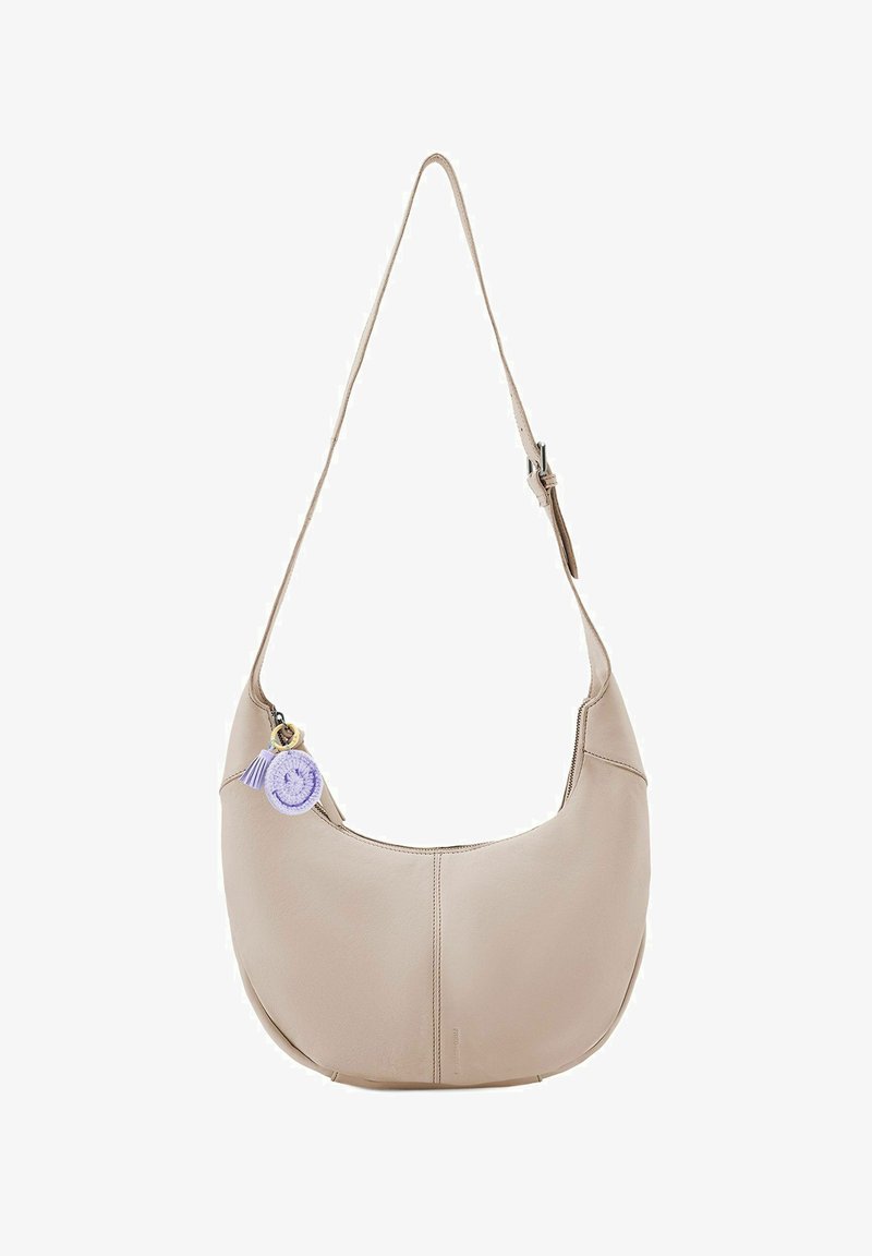 Bolso de hombro de cuero beige con una forma curva y suave. Presenta un tassel decorativo morado y un charm adjunto a la cremallera. Correa ajustable.