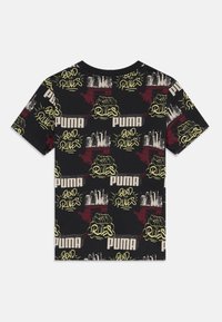 Svart kortermet t-skjorte i bomull med et livlig grafisk trykk med gul og rød tekst, samt forskjellige motiver, inkludert "PUMA"-logoen.