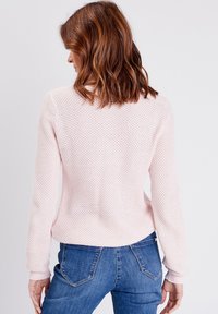 Helles rosa gestricktes Sweatshirt mit einem strukturierten Muster und langen Ärmeln. Der Rücken weist einen dezenten Rundhalsausschnitt und gerippte Bündchen auf.