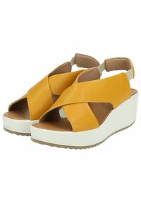 Sandali wedge gialli in pelle con un design a bande incrociate, punta aperta, cinturini imbottiti alla caviglia e una suola piatta bianca.