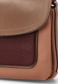 Bolso de hombro de cuero marrón con una solapa superior lisa, un panel burdeos texturizado y costuras en contraste a lo largo de los bordes.