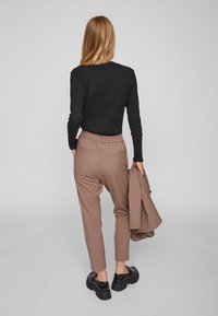 Mustra mustriga pikkade varrukatega topp, beežid kõrge vöökoha püksid elastse vööga ja tagakottidega, mustad platvormkingad, hoides sobivat bleiserit.