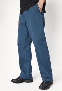 Blue cotton pants with a straight leg design, featuring side pockets and a smooth texture; paired with black athletic shoes.