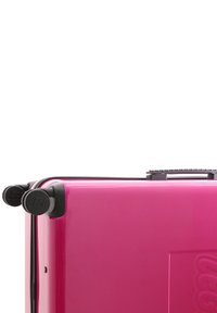 Pink hard-shell suitcase with a glossy finish, featuring black LEGO logo wheels and zipper accents. Rectangular shape, sturdy handle on top.