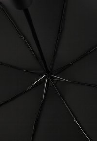 Zwarte paraplu met een gladde, matte stoffen kap, metalen baleinen en een centraal scharnierpunt. De textuur oogt strak en heeft een minimalistisch ontwerp.