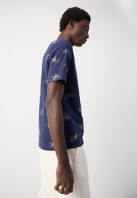 T-shirt blu navy con motivo di barche a vela giallo e bianco, realizzato in morbido cotone, colletto a girocollo, maniche corte e vestibilità rilassata.