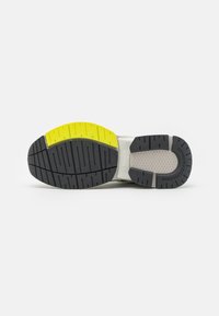 Sole di scarpa con un battistrada in gomma nera, caratterizzata da una sezione gialla e accenti grigio chiaro. Texturizzata con scanalature per una migliore presa.