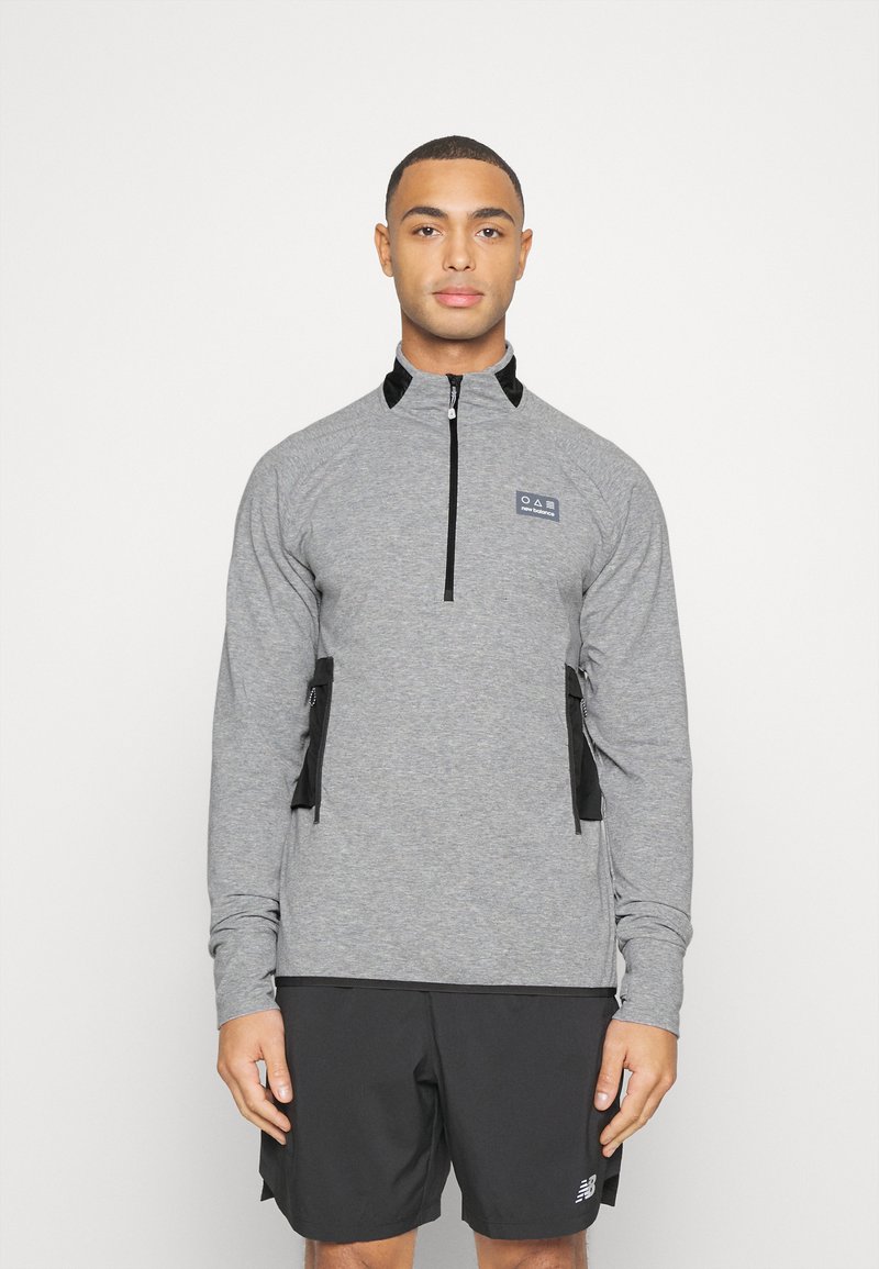 Sudadera gris con cremallera y mangas largas, con acentos en negro y bolsillos. Fabricada en una tela suave, cuenta con un cuello y un logotipo en el pecho.