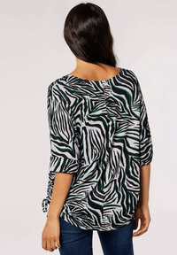 Zwart, wit en groen gestreepte top met zebramotief, driekwart mouwen, zachte stof, ronde halslijn en zijstrikjes aan de zoom.