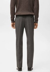 Pantalones grises a medida con una textura suave, piernas rectas y bolsillos traseros, combinados con un suéter marrón con relieve de canalé.