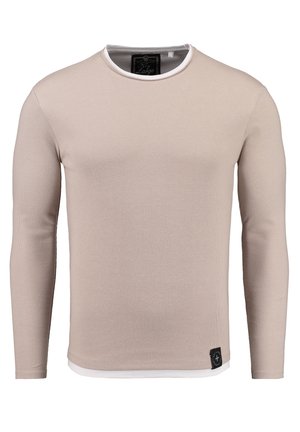 Chemise à manches longues beige clair avec une texture côtelée, col rond, et bord contrasté blanc. Présente une petite étiquette logo noire au niveau de l'ourlet.