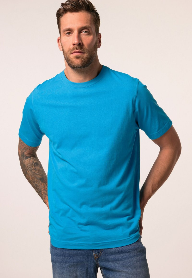 Una T-shirt azzurra a maniche corte realizzata in morbido cotone, con scollatura rotonda e vestibilità comoda, abbinata a jeans blu.