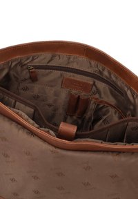 Interno di borsa in pelle marrone con fodera in tessuto liscio, dotato di tasca con cerniera, slot per carte e dettagli marchiati in un motivo sottile.