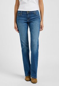 Jeans acampanados de mezclilla azul, con un diseño clásico de cinco bolsillos, cierre de botón y costuras en contraste a lo largo de las costuras.