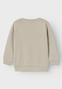 Bežinis džemperis su apvalia iškirpte, ilgomis rankovėmis, mega galia ir juostos. Lygi tekstūra, minimalistinis dizainas ir nematomi raštai.