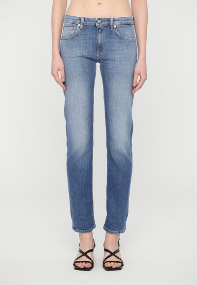 Light blue denim jeans with a straight leg fit, featuring front pockets, a button closure, and subtle fading. Paired with black strappy sandals.