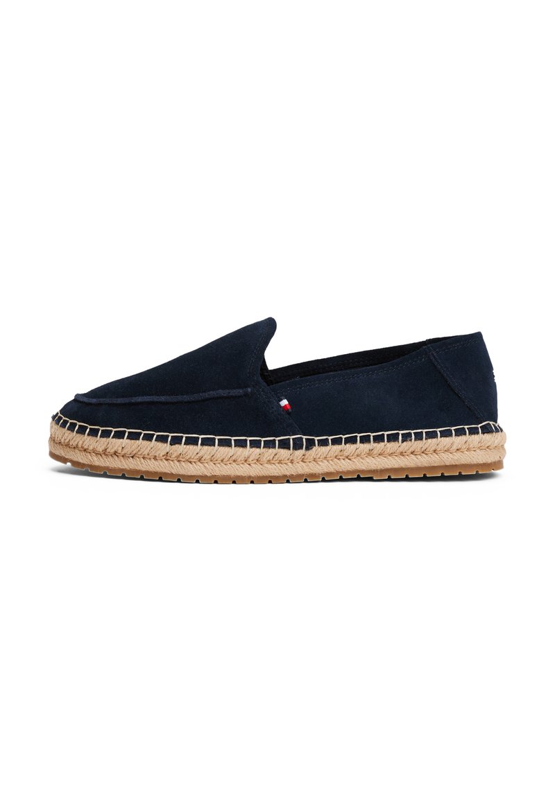 Zapato sin cordones de ante azul marino con suela de cuerda de yute, que presenta una puntera redondeada y sutiles detalles de costura a lo largo de la parte superior.