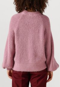 Roze gebreide trui met een zachte, gestructureerde afwerking. Bevat een geribde onderrand, raglanmouwen en een ontspannen pasvorm, ontworpen voor comfort.