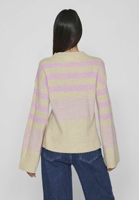 Beige tröja med rosa och lavendel horisontella ränder, oversized passform, ribbade ärmslut och nederkant, mjuk stickad struktur, bärs med mörka jeans.