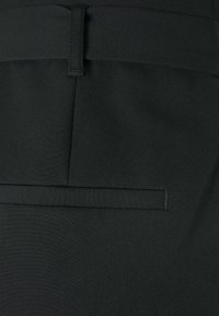 Zwarte stoffen broek met een soepele textuur, voorzien van riemlussen, achterzak en een vlakke voorkant. Effen, zonder zichtbare patronen.