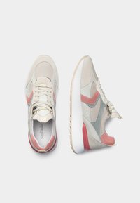 Sneaker beige con pannelli in rete e suede, con accenti rosa e grigi, suola bianca e lacci rotondi. Superficie texturizzata e design affusolato.
