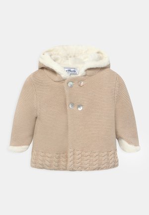 Veste bébé beige tricotée avec double boutons, ourlet torsadé, capuche et poignets doublés en polaire blanche.