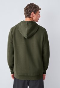 Sudadera con capucha verde oliva con un patrón texturizado de diamantes. Cuenta con capucha con cordón y puños acanalados, ofreciendo un ajuste relajado.