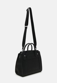 Czarna torebka z podwójnymi uchwytami i regulowanym paskiem. Wykonana z teksturowanej tkaniny z srebrnymi akcesoriami i wyraźnym kształtem. Detal kieszeni na froncie.