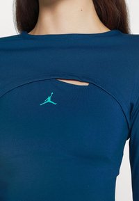 Námořnická dlouhá mikina s kulatým výřezem na výstřihu, se tyrkysovým logem Jordan na hrudi. Vyrobena z hladké, elastické tkaniny.